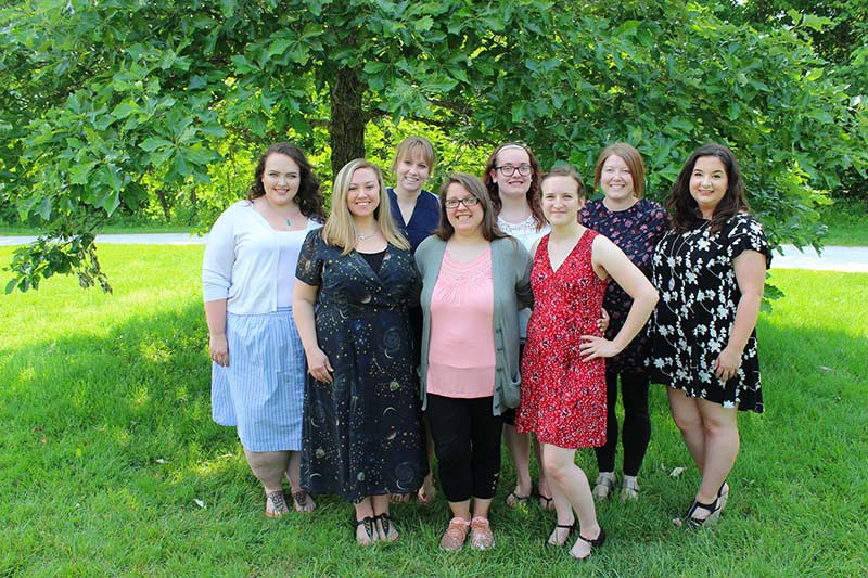 Learning Star Preschool staff standing outside in the grass in front of a tree, three teachers in front (with the owner, Michelle), 5 teachers in back